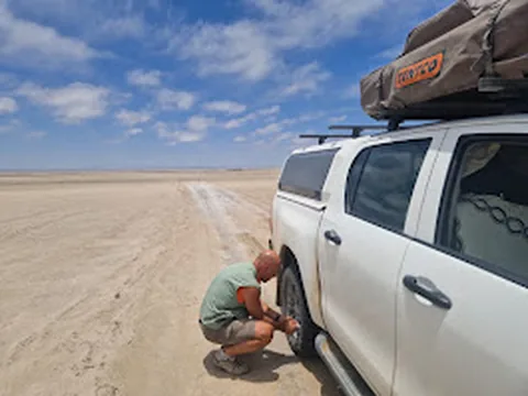 Client checking tyre pressure on a Namib Trails 4x4 in the desert