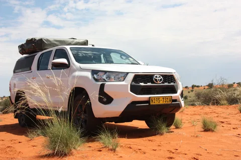 Namib Trails 4x4 Toyota Hilux driving on red sand dunes in Namibia
