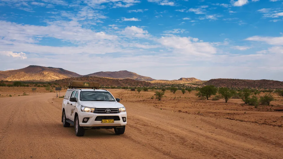 Namib Trails 4x4 Toyota Hilux on gravel road with mountains in the background