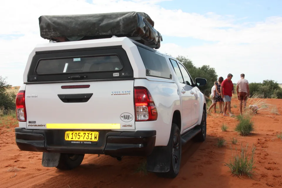 Rear view of Namib Trails 4x4 Toyota Hilux with clients in the desert